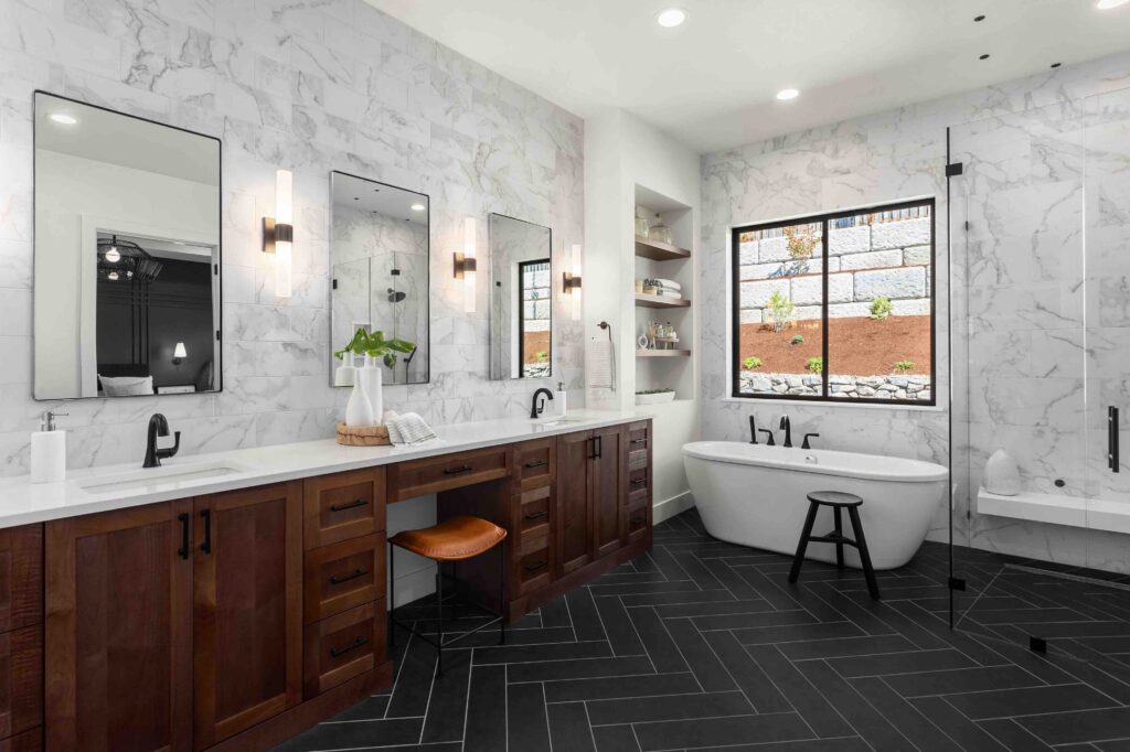 Beautiful bathroom in luxury home with double vanity, bathtub, and shower. Features herringbone tile on floor and marble tile on wall and backsplash.