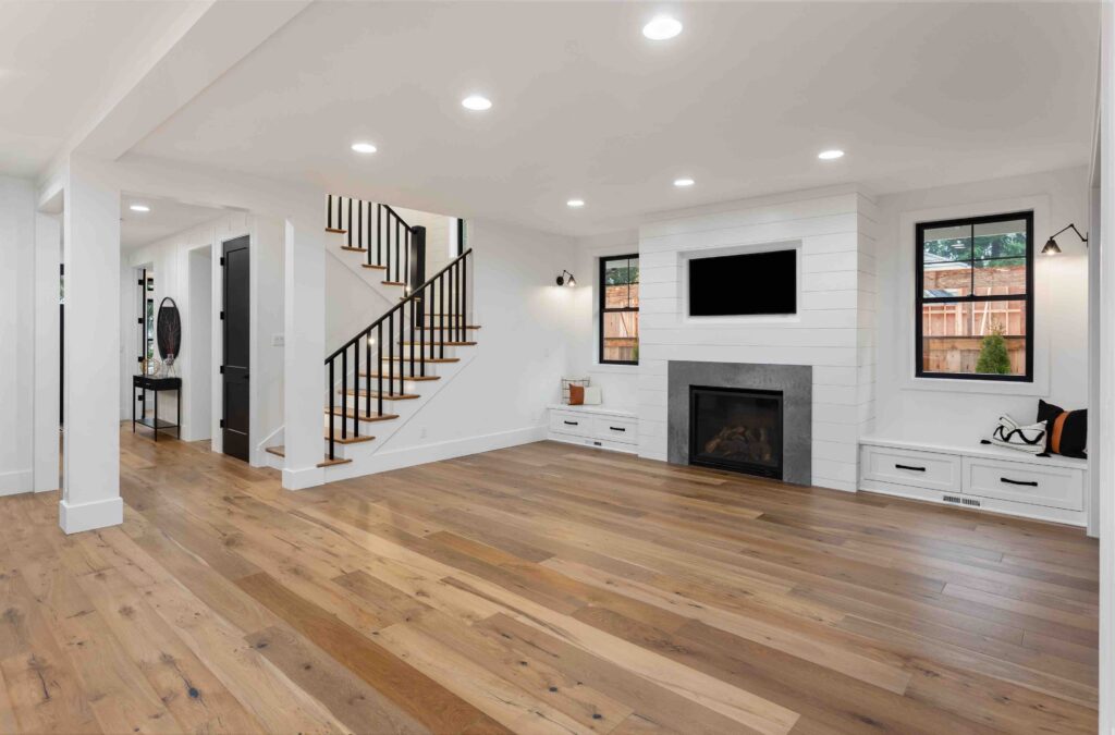 Beautiful white farmhouse style living room in new luxury home. Features hardwood floors, white shiplap, fireplace, and built-in with tv.