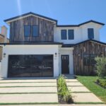 Modern home remodel in Los Angeles with wood siding, white exterior, and black garage door by Buildwright Construction